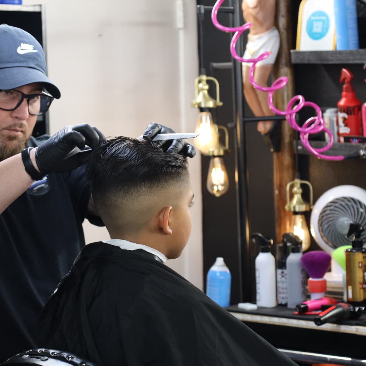 Adriano blending a fade with clippers and a comb at the chair